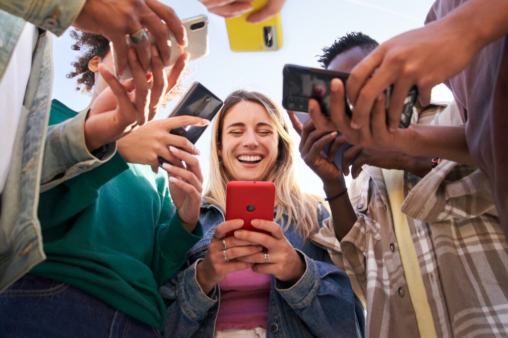 Vista de baixo ângulo de um grupo de jovens adolescentes usando telefones celulares. Conceito de tecnologia, conexão.